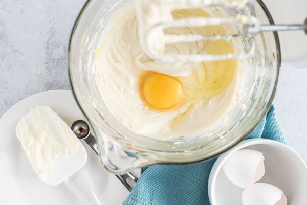 Mixing the eggs one at a time into the cheesecake batter