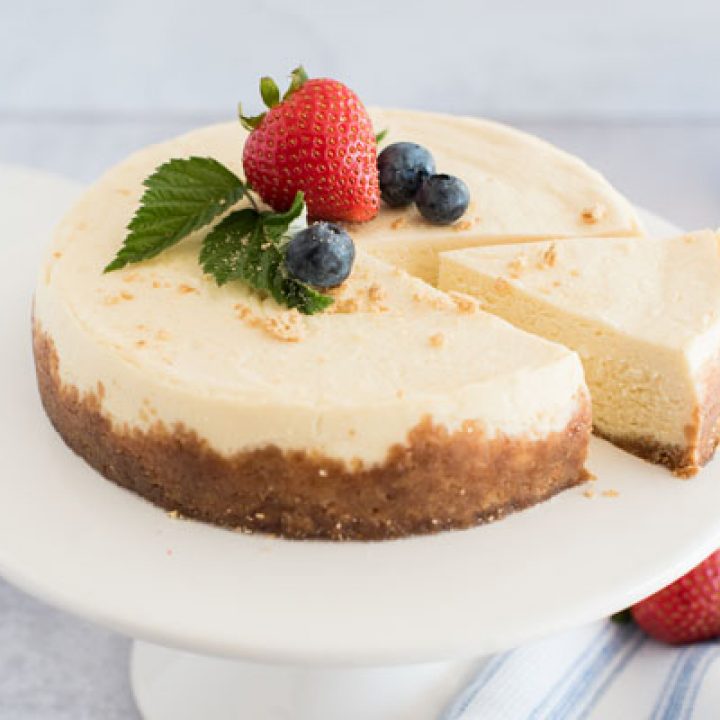 Pressure cooker cheesecake on a cake stand, sliced and ready to serve.