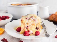 Pressure Cooker Raspberry Orange Bread Pudding, dished up with the cake pan and bowl of raspberries in the background