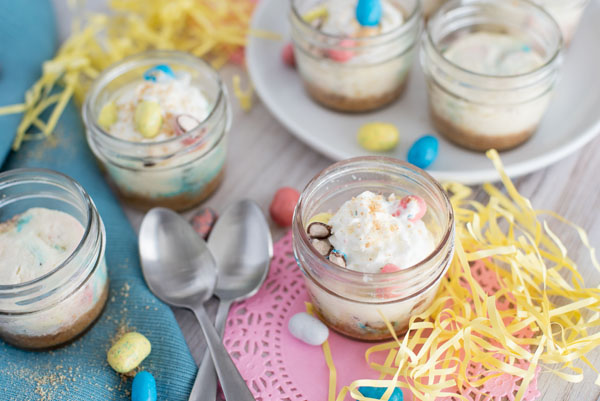 Individual Robin Egg Cheesecakes flavored with Whoppers Robin Eggs for Easter with Easter colored decorations and metal spoons