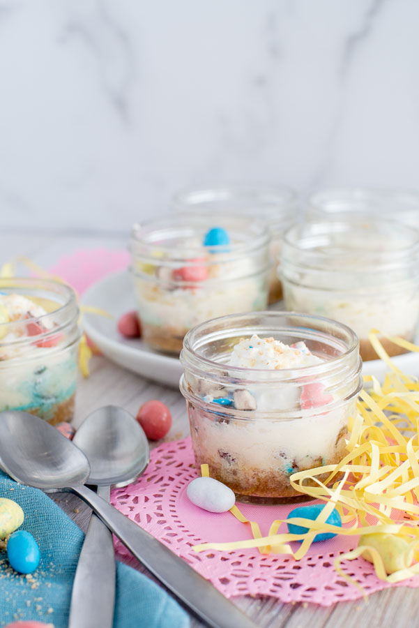 Side view of multiple mini Robin Egg Cheesecakes baked in a pressure cooker in individual glass mason jars for Easter.