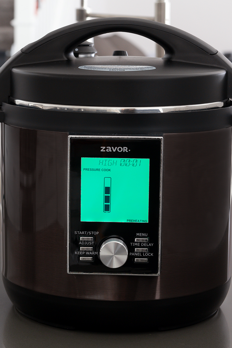 The Zavor LUX pressure cooker with the LCD screen showing the status for coming to pressure.