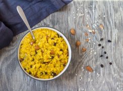 Instant Pot Saffron Risotto with Almonds and Currants in a white bowl with spoon