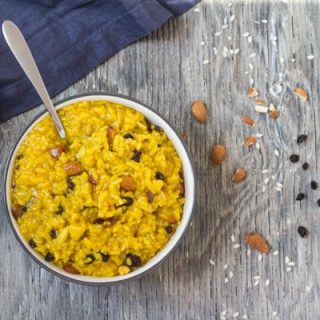 Instant Pot Saffron Risotto with Almonds and Currants in a white bowl with spoon