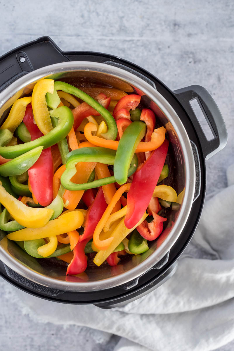 Uncooked peppers in and Instant Pot for a sausage and peppers recipe.