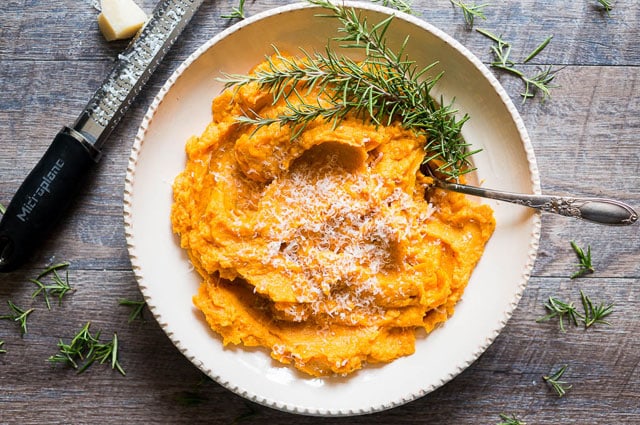 white bowl of Savory Mashed Sweet Potatoes with parmesan cheese and fresh herbs