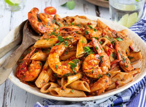 Close up on a large white serving plate of pressure cooker / Instant Pot Shrimp Fra Diavlo over penne pasta topped with fresh parsley.