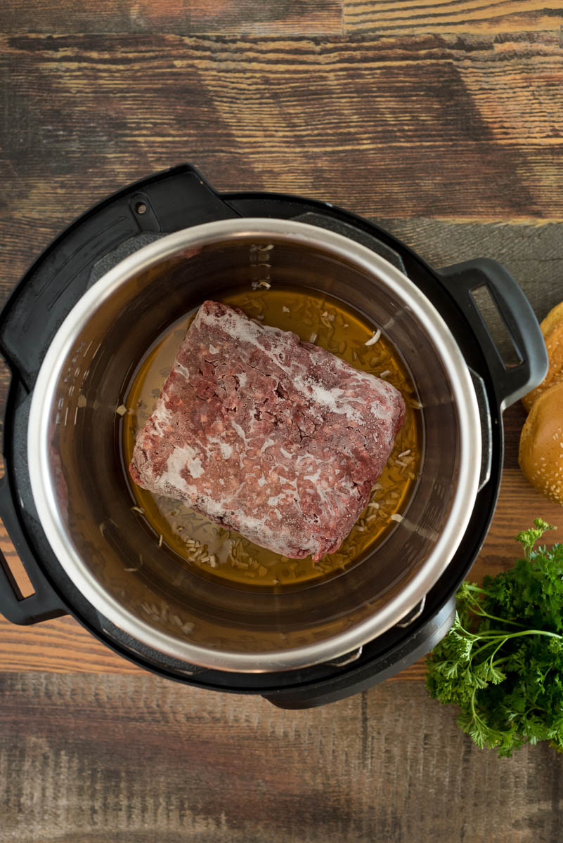 Frozen beef with beef broth placed in an Instant Pot for easy sloppy joes.