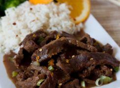 Pressure Cooker (Instant Pot) Spicy Orange Beef with a side of rice and an orange slice on a white serving dish