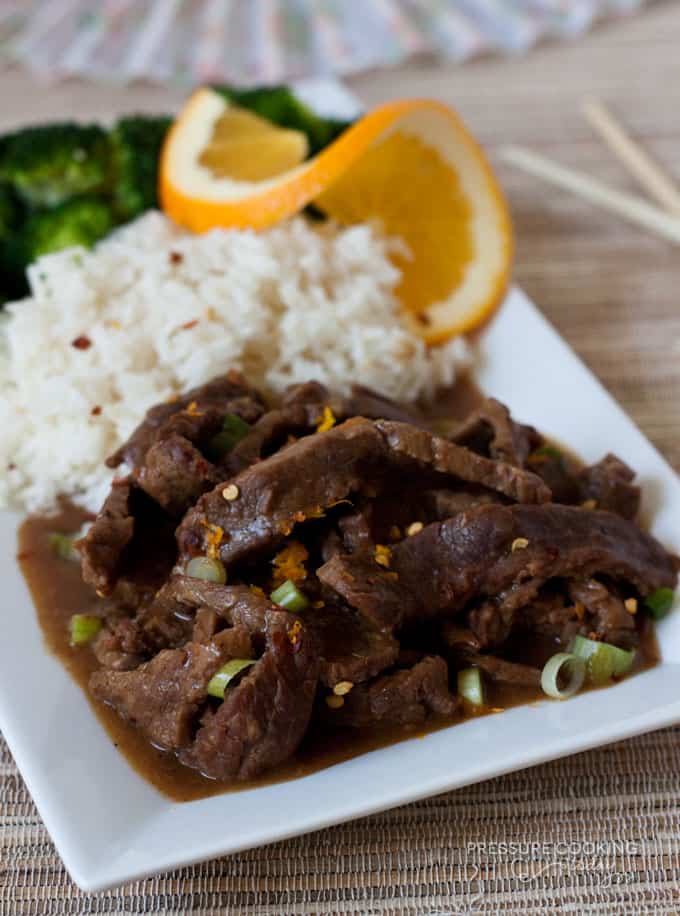 Pressure Cooker (Instant Pot) Spicy Orange Beef with a side of rice and an orange slice on a white serving dish