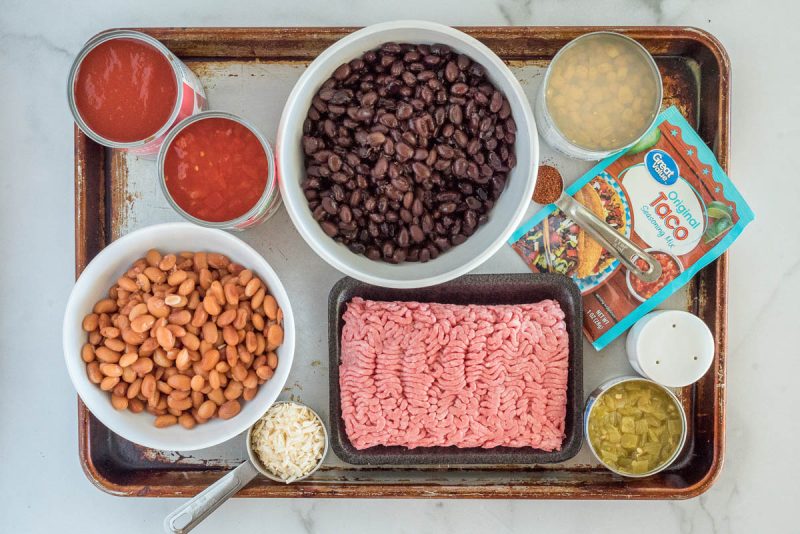 Ingredients for Instant Pot taco soup, including green chilis, taco seasoning, black beans, pinto beans, dehydrated onion, ground beef and diced tomatoes.