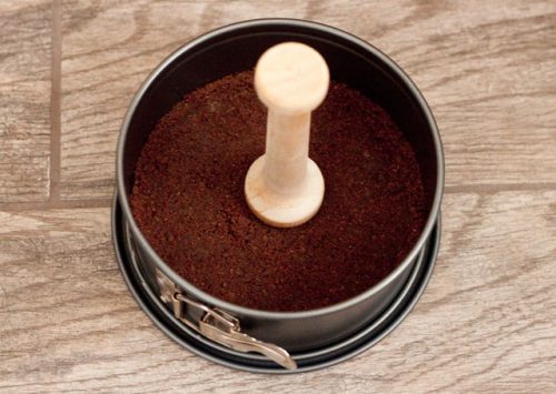 tamper tool being used on peanut butter cup cheesecake crust