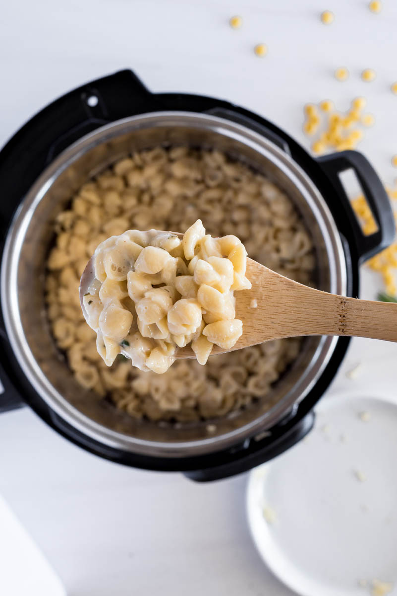 overhead of an instant pot with creamy mac and cheese on a wooden spoon